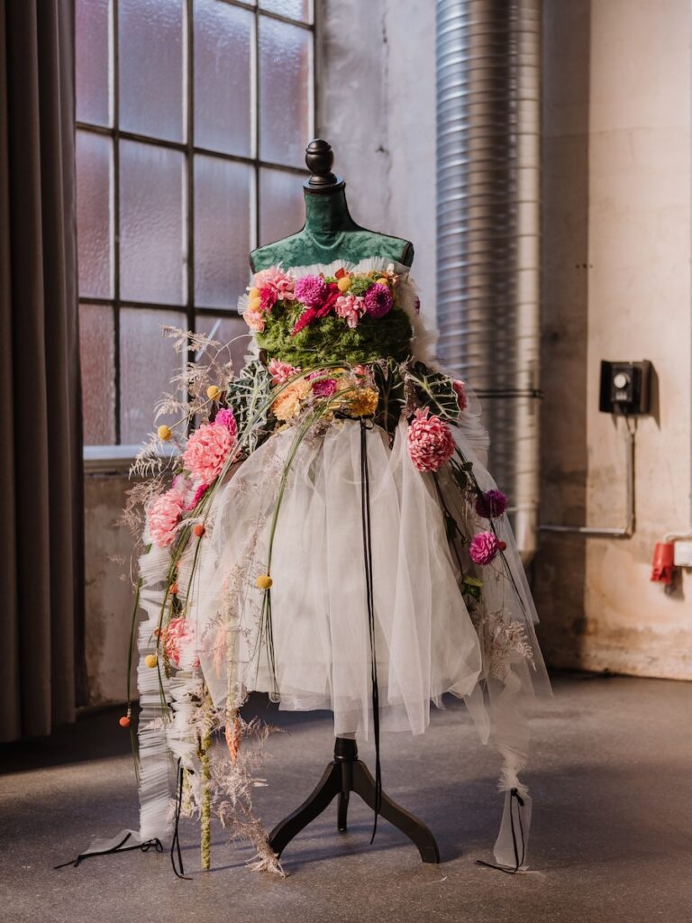 woman in white and pink floral dress holding bouquet of flowers